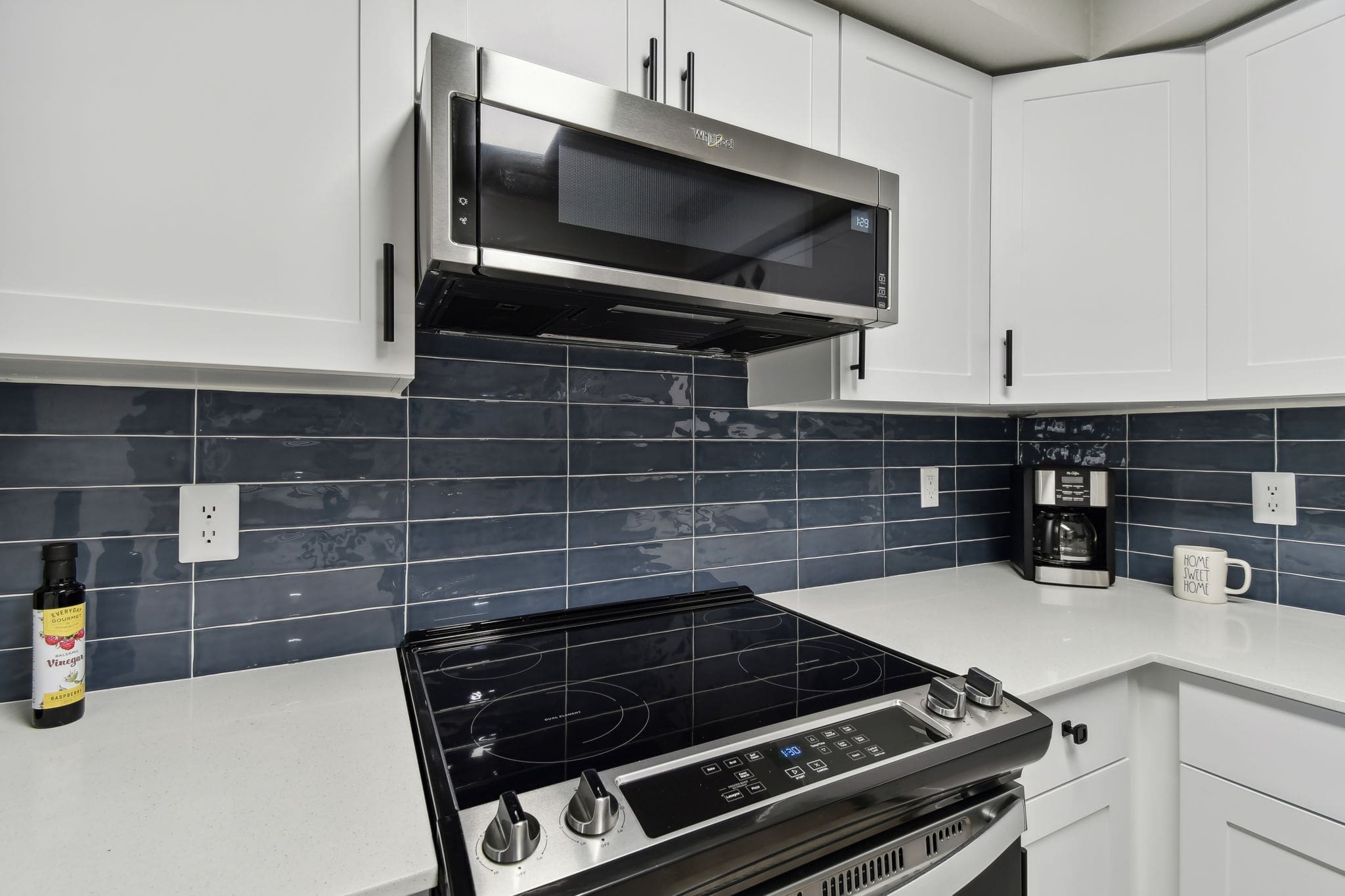 1 Bedroom Luxury Apartments In Winter Springs, FL - Eli Winter Springs - A Kitchen With Wood-Style Flooring, Spacious White Quartz Countertops, Stainless Steel Appliances, And White Cabinetry.